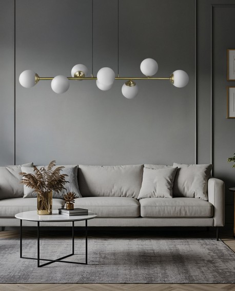 Lampa wisząca w szczotkowanym złocie z sześcioma białymi kulami, zawieszona nad szaro-beżową sofą w nowoczesnym salonie