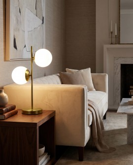 Stylowa lampa stołowa w kolorze mosiądzu i bieli podkreślająca wystrój nowoczesnego salonu