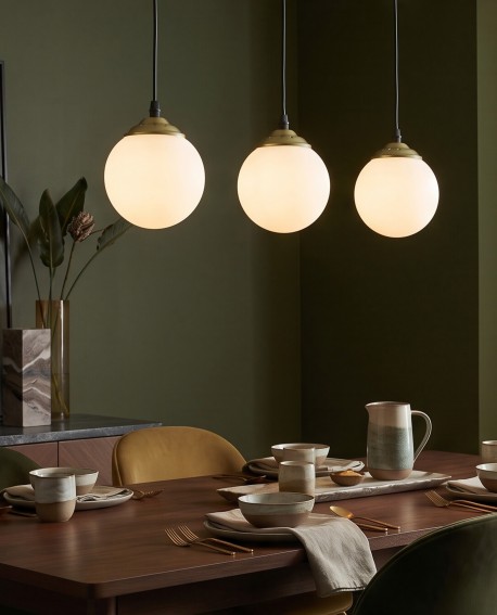Nowoczesna złota lampa z mlecznymi szklanymi kloszami zawieszona nad stołemNowoczesna złota lampa z mlecznymi szklanymi kloszami