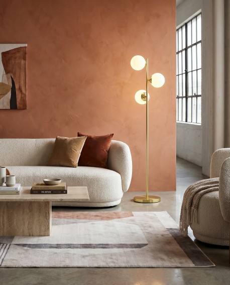 Złota lampa stojąca FINO W3 marki Lampit z trzema kulistymi kloszami w salonie przy sofie