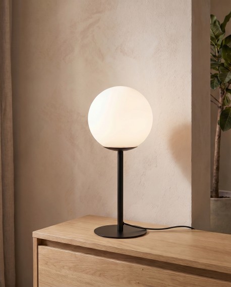 Czarna metalowa lampa z białą kulą ozdabia pokój dzienny
