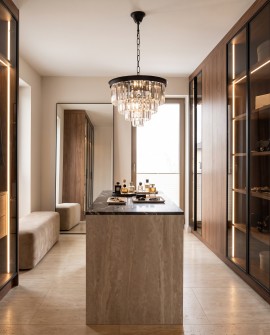 Lampa wisząca glamour z kryształami nad wyspą w jasnej, nowoczesnej garderobie