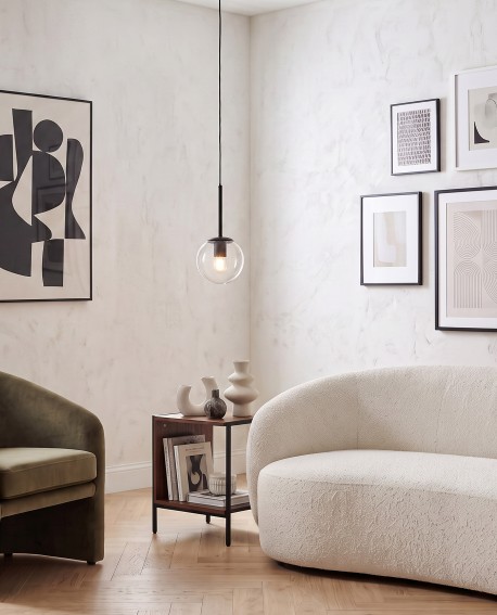 Czarna lampa wisząca z przezroczystą szklaną kulą nad stolikiem w eleganckim salonie