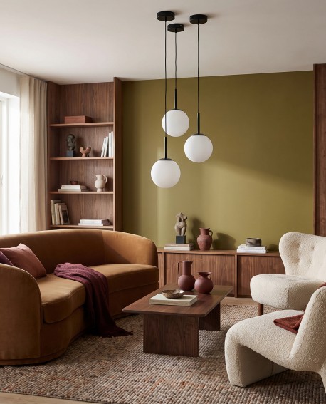 Nowoczesna lampa wisząca w salonie z brązową sofą i zieloną ścianą