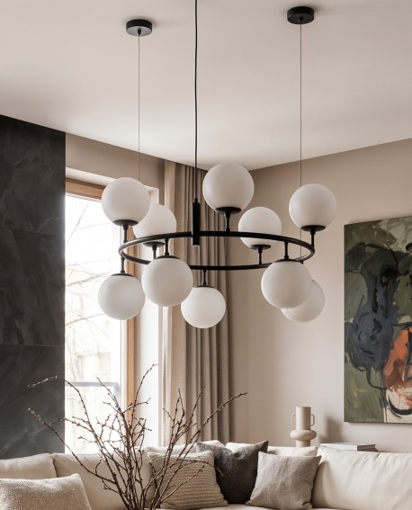 Okrągła lampa wisząca z mlecznymi kulami doświetla przestronny salon z dużym oknem
