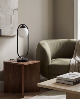 Czarna lampa z białą kulą na stoliku pomocniczym w strefie relaksu