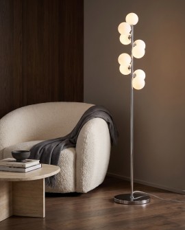 Chromowana lampa podłogowa PETRICA W9 z kulami obok jasnego fotela w salonie